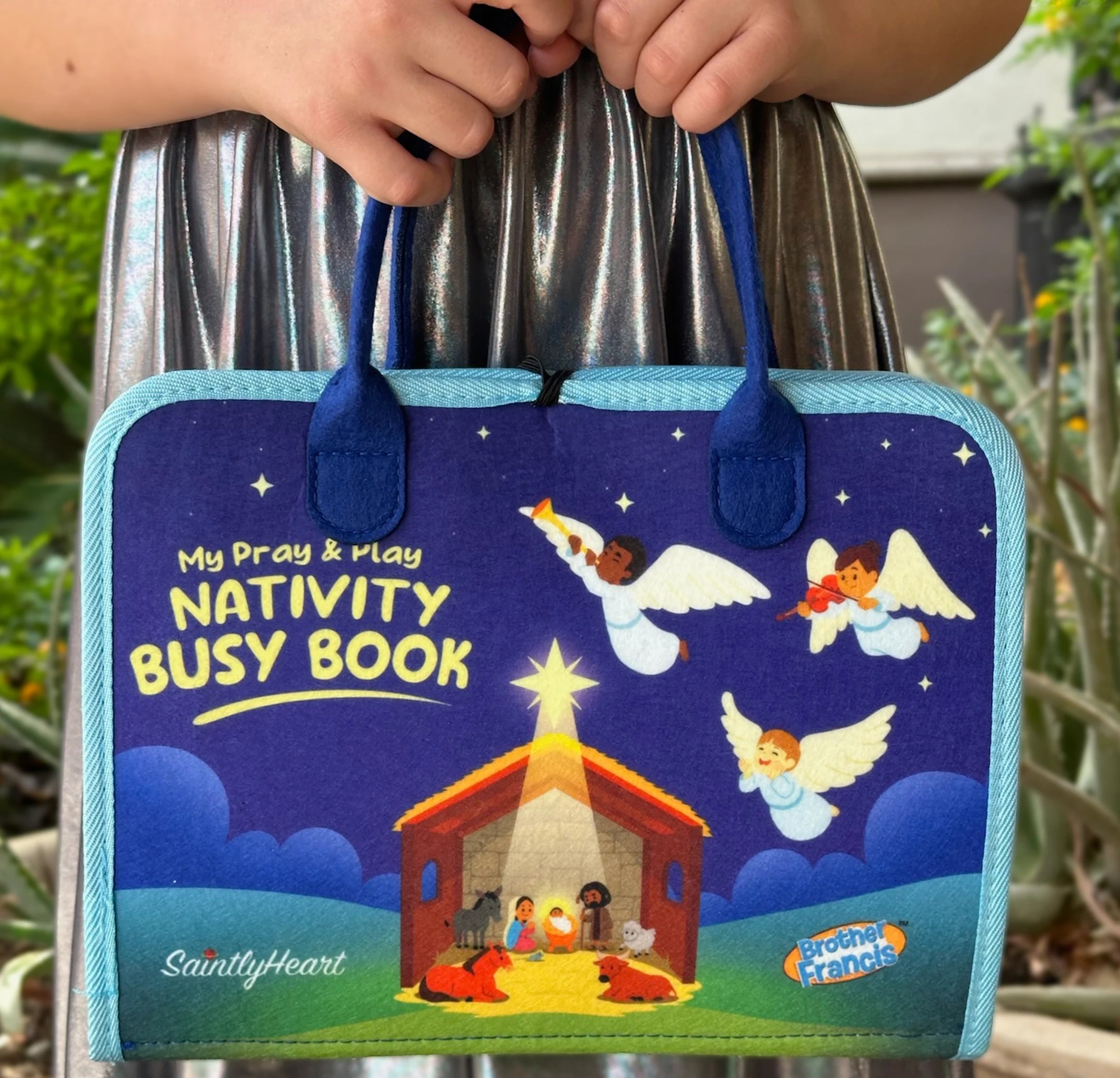 girl holding my pray and play nativity busy book