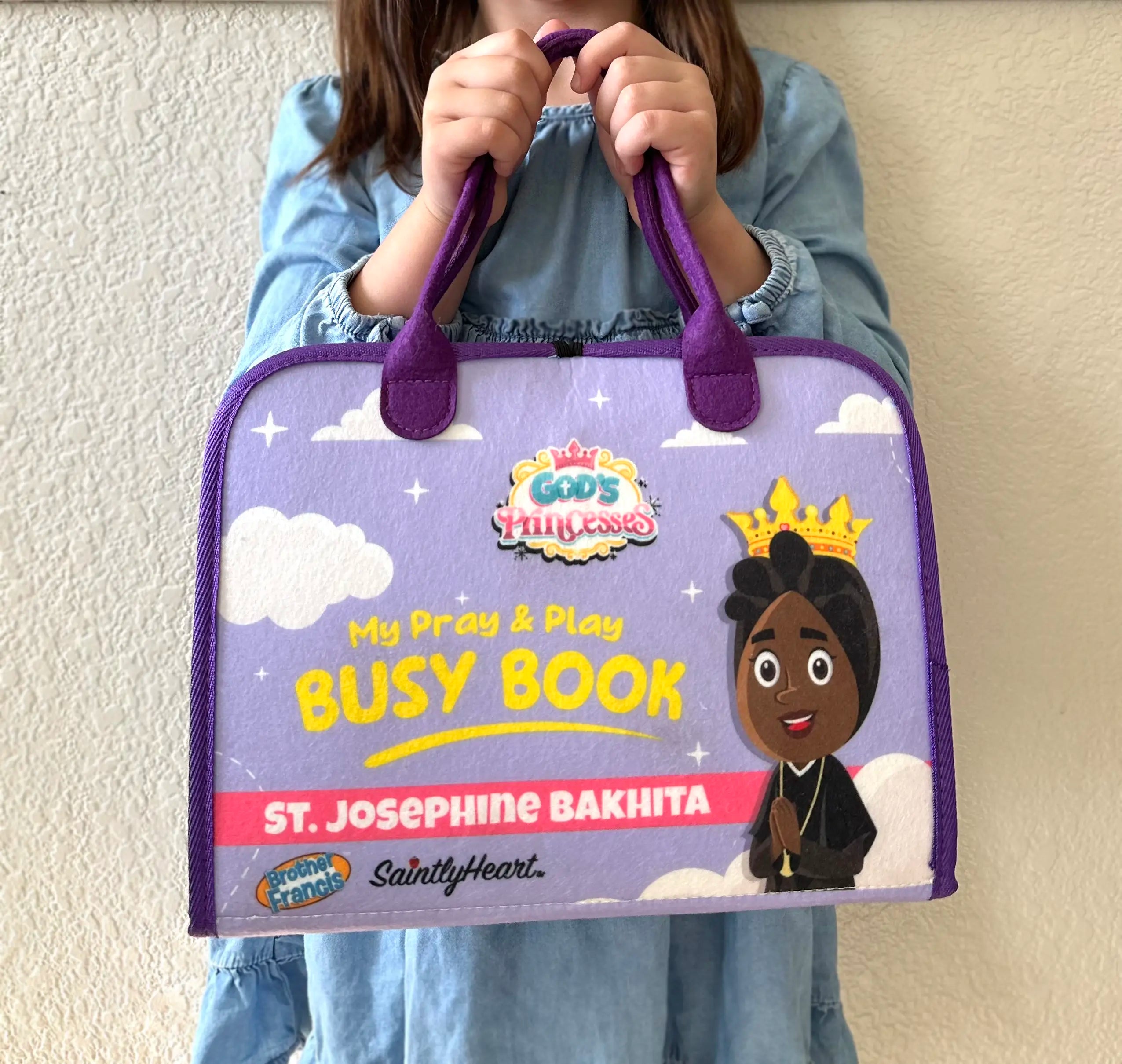 girl holding purple felt busy book with saint bakhita on cover